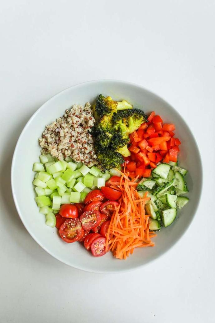 Assiette blanche avec des crudités, brocolis et quinoa que fond blanc