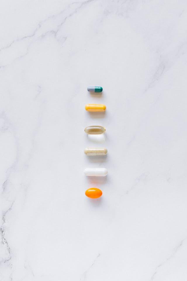 Compléments alimentaires en gélules, capsules blanches et de couleurs alignées verticalement