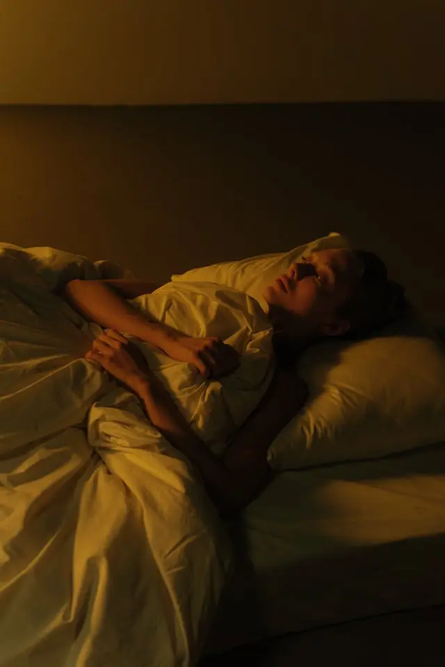 Femme qui dort sur le dois avec couette et oreillers blancs
